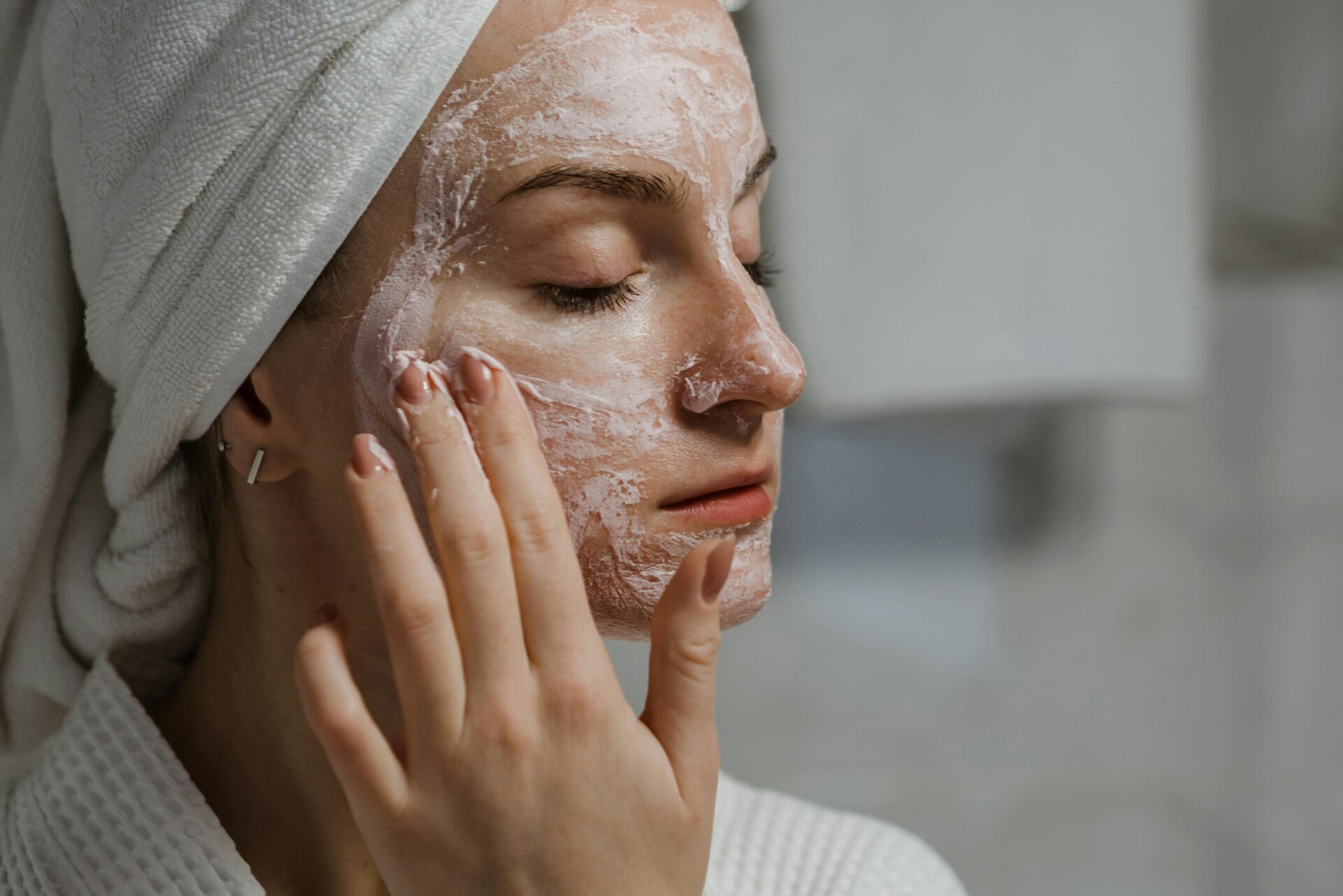 Una mujer aplicando una mascarilla de arcilla como parte de su régimen de belleza de cuidado personal en interiores.