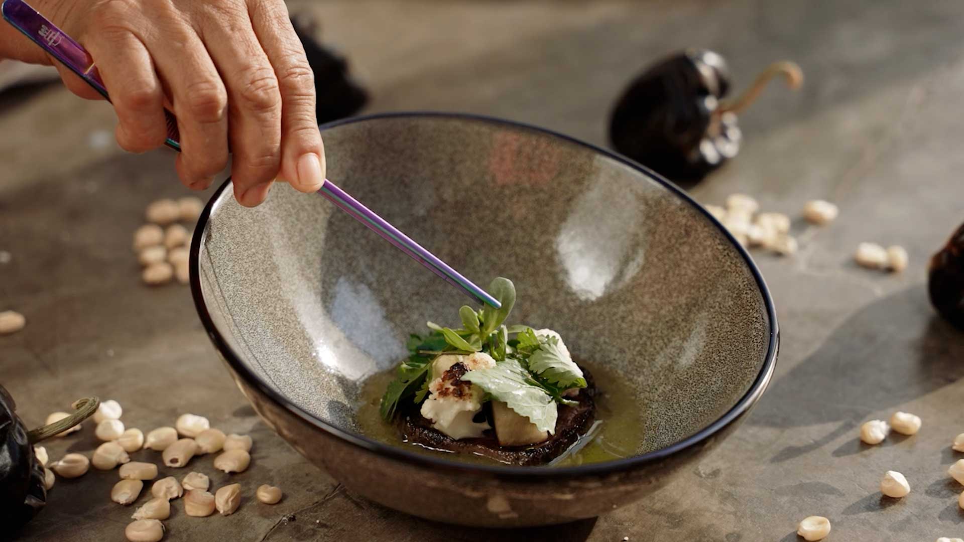 una persona sosteniendo un palillo en un plato de comida