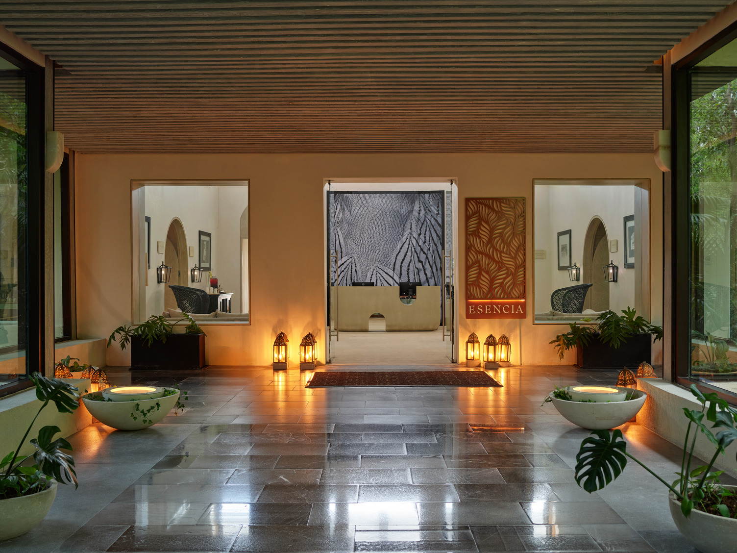 Luxurious spa entrance at UNICORM_Esencia_Wellness with glowing lanterns, serene decor, and large potted plants.